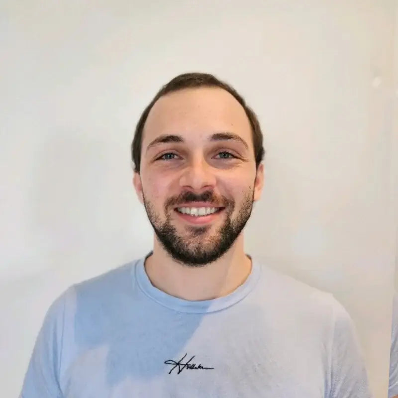 Daniel Perera, the founder of the ShopiCraft agency building Shopify stores and solutions in a blue t-shirt with a white background.